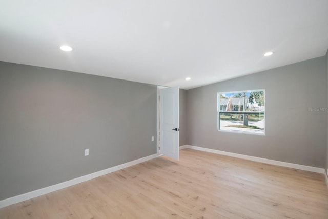 empty room featuring vaulted ceiling and light wood-type flooring