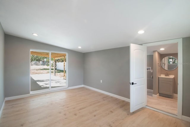 spare room featuring lofted ceiling, sink, and light wood-type flooring