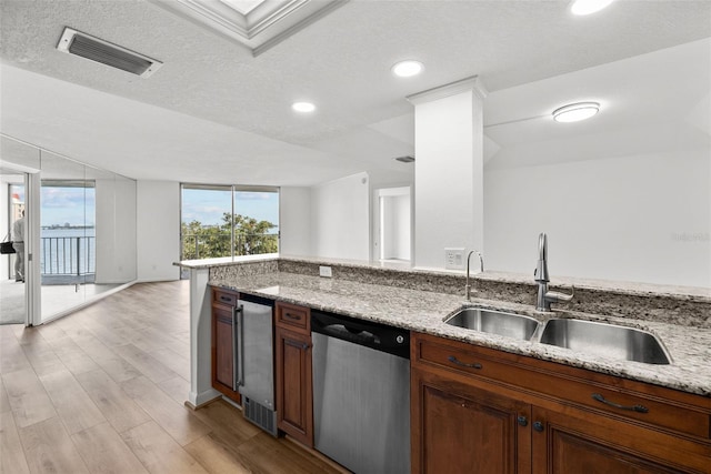 kitchen featuring stainless steel dishwasher, plenty of natural light, a textured ceiling, and light hardwood / wood-style flooring