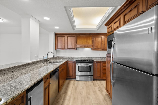 kitchen featuring light stone countertops, appliances with stainless steel finishes, light wood-type flooring, custom exhaust hood, and sink