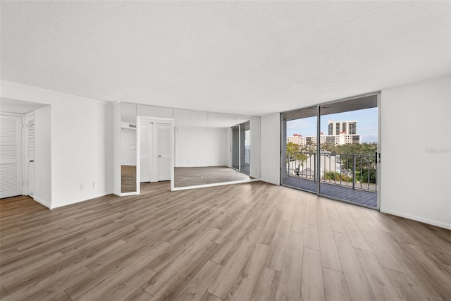 interior space featuring a wall of windows, a textured ceiling, and light wood-type flooring