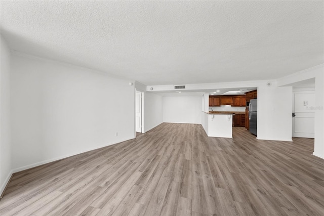 unfurnished living room featuring a textured ceiling and light hardwood / wood-style floors