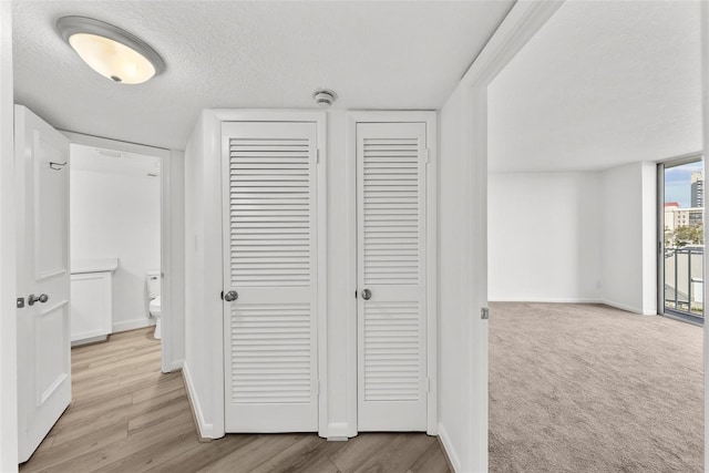 hall featuring a textured ceiling and light wood-type flooring