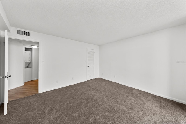 unfurnished room featuring dark colored carpet and a textured ceiling