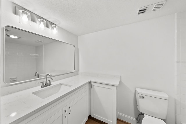 bathroom featuring hardwood / wood-style flooring, vanity, toilet, and a textured ceiling