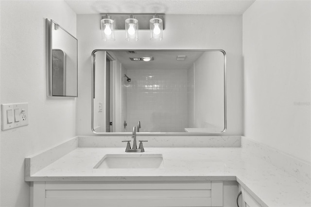 bathroom featuring a tile shower and vanity