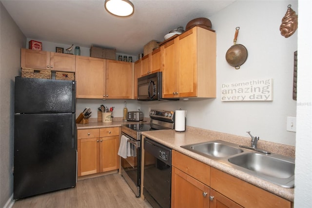 kitchen with black appliances, sink, and light hardwood / wood-style flooring