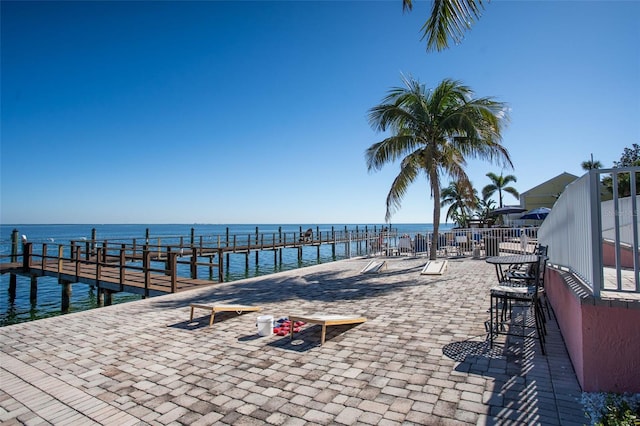 view of pool with a patio area, a water view, and a boat dock