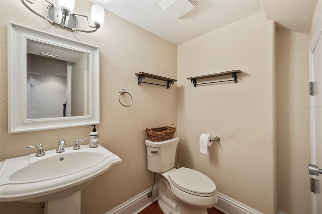 bathroom featuring a textured ceiling, toilet, and sink