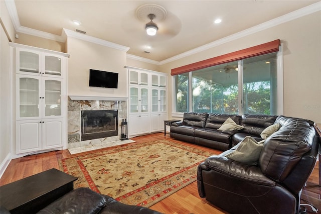 living room with a tile fireplace, crown molding, hardwood / wood-style floors, and ceiling fan