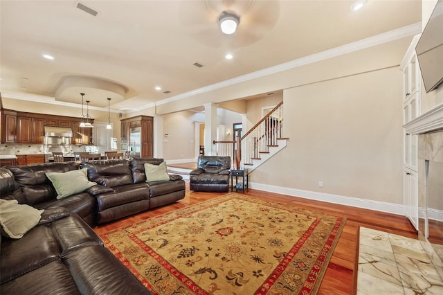 living room with ceiling fan, light hardwood / wood-style floors, ornamental molding, and ornate columns