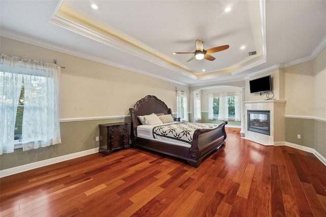 bedroom with hardwood / wood-style floors, a tray ceiling, and ceiling fan