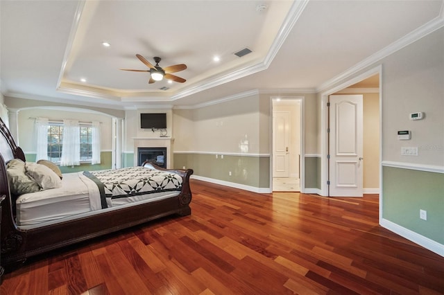 bedroom featuring a tray ceiling, ceiling fan, hardwood / wood-style floors, and ornamental molding