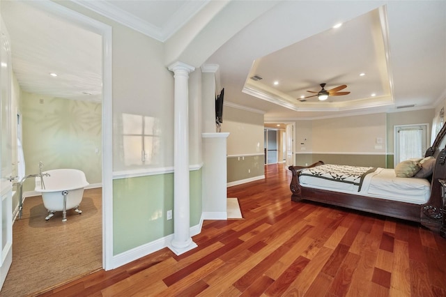 bedroom featuring ceiling fan, decorative columns, crown molding, a tray ceiling, and hardwood / wood-style flooring