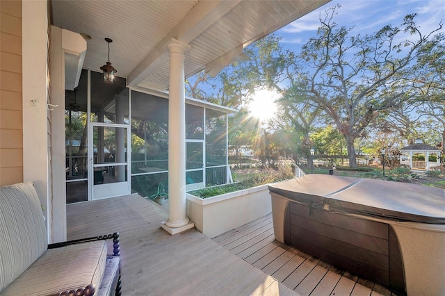 deck featuring a covered hot tub and a sunroom