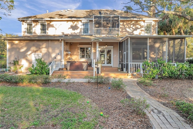 back of property with a sunroom and a hot tub