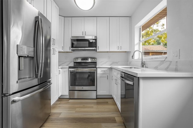 kitchen featuring white cabinets, light wood-type flooring, sink, and appliances with stainless steel finishes