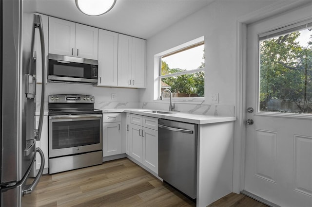 kitchen with white cabinets, sink, stainless steel appliances, and a wealth of natural light