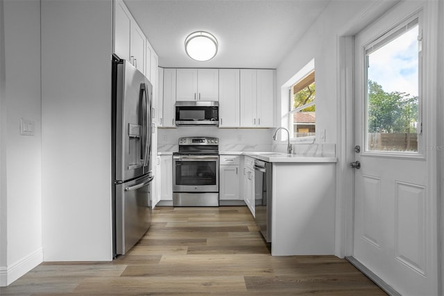 kitchen with white cabinets, appliances with stainless steel finishes, light hardwood / wood-style flooring, and sink