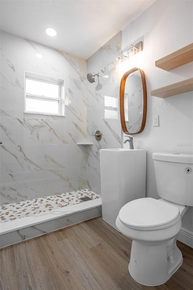 bathroom with a tile shower, hardwood / wood-style flooring, and toilet