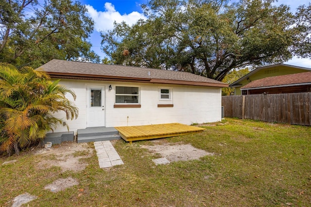 back of property featuring a wooden deck and a yard