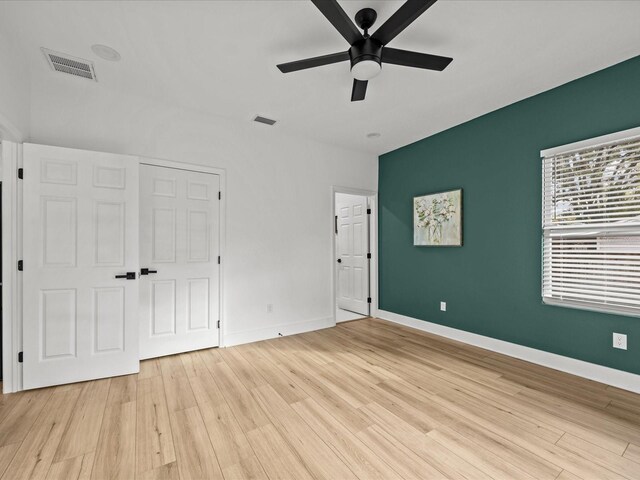 unfurnished bedroom with ceiling fan, light wood-type flooring, and a closet