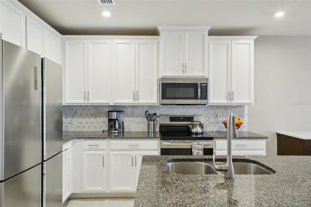 kitchen with dark stone countertops, sink, and appliances with stainless steel finishes