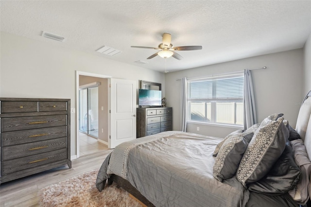 bedroom with ceiling fan, light hardwood / wood-style floors, and a textured ceiling