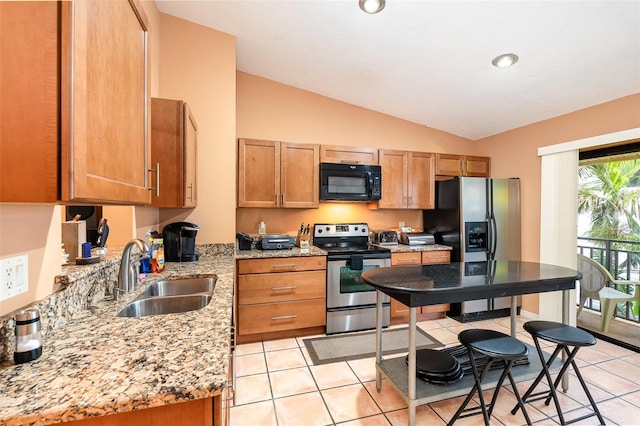 kitchen with appliances with stainless steel finishes, light stone counters, sink, light tile patterned floors, and lofted ceiling