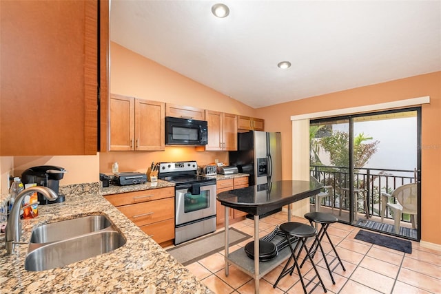 kitchen featuring light stone countertops, appliances with stainless steel finishes, vaulted ceiling, sink, and light tile patterned floors