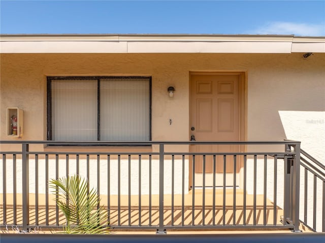 view of exterior entry featuring stucco siding and a balcony