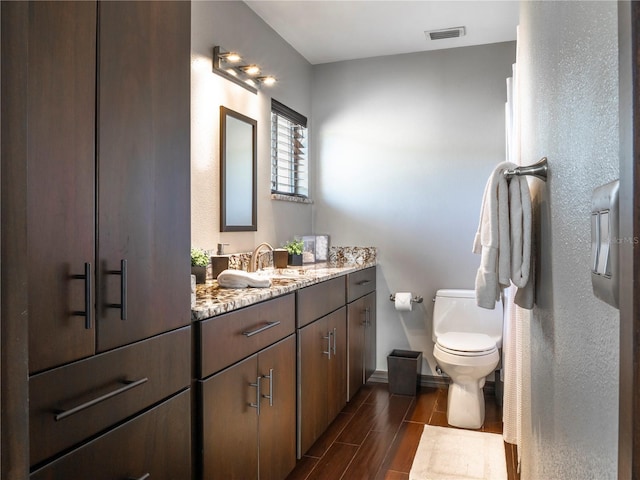 bathroom featuring visible vents, toilet, wood tiled floor, baseboards, and vanity