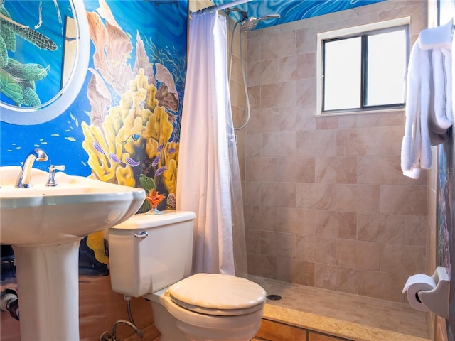 full bathroom featuring tiled shower and toilet