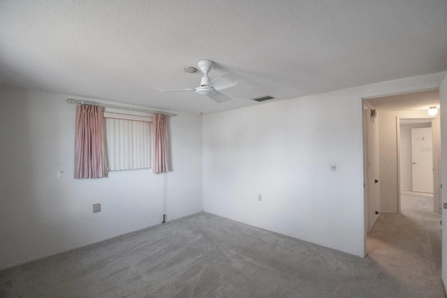 carpeted empty room with ceiling fan and a textured ceiling