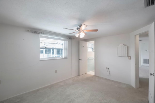 carpeted spare room with a textured ceiling and ceiling fan