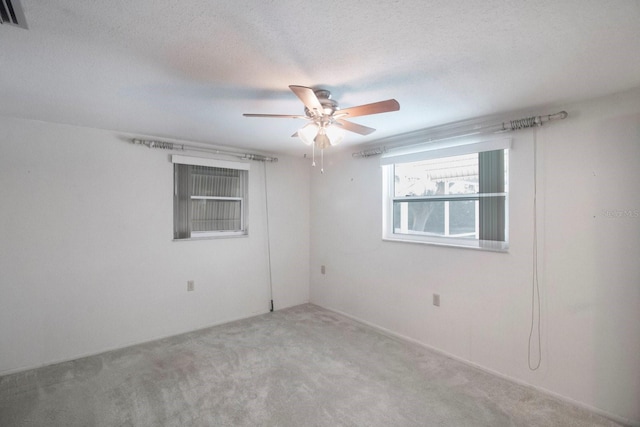 carpeted spare room featuring ceiling fan and a textured ceiling