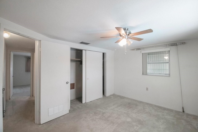 unfurnished bedroom with light carpet, a closet, and ceiling fan