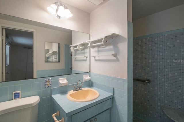 bathroom featuring vanity, toilet, tile walls, and a tile shower