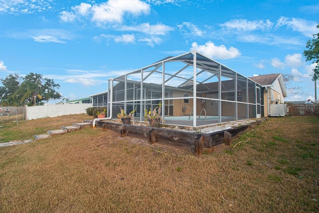 back of house with glass enclosure and a yard