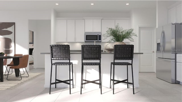 kitchen with a breakfast bar, light tile patterned floors, white cabinetry, and appliances with stainless steel finishes