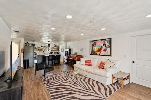 living room with a textured ceiling and light wood-type flooring