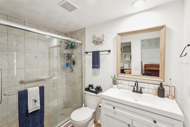 bathroom featuring vanity, toilet, walk in shower, and tasteful backsplash