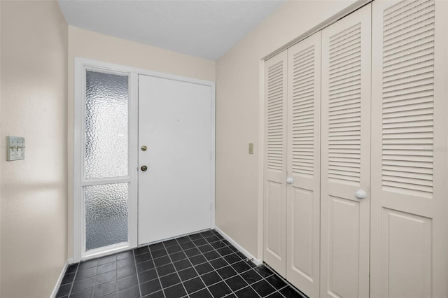 foyer featuring dark tile patterned floors