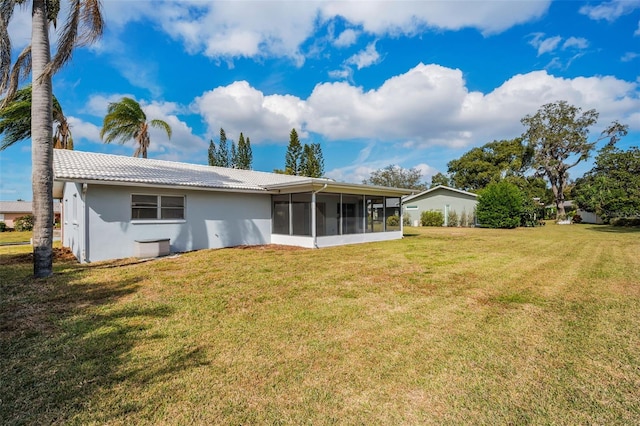 rear view of house featuring a lawn and a sunroom