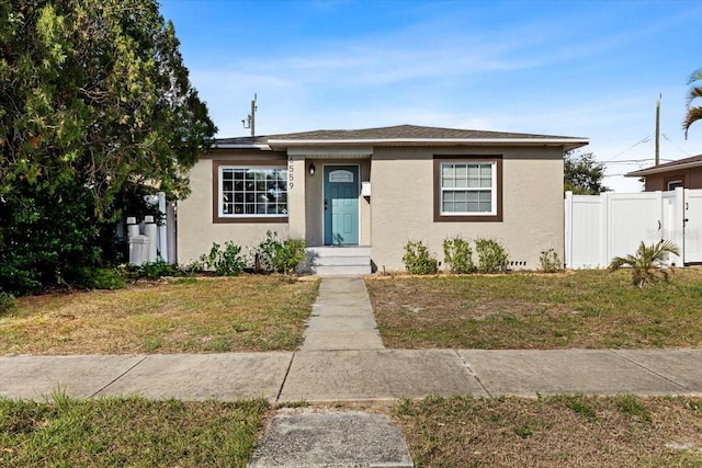 bungalow with fence, a front lawn, and stucco siding