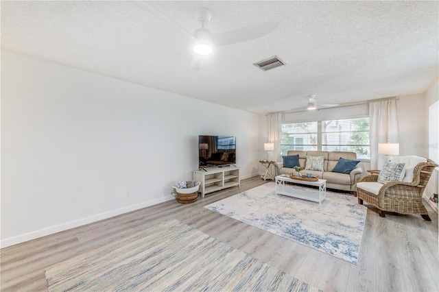 living room featuring a textured ceiling, light hardwood / wood-style floors, and ceiling fan