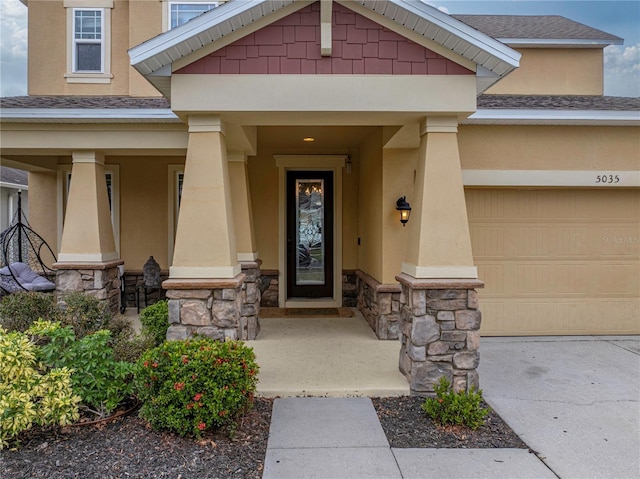 view of exterior entry with covered porch and a garage