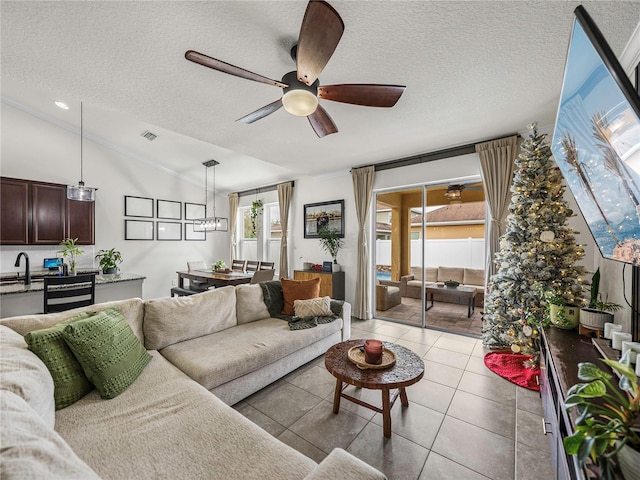 tiled living room with plenty of natural light, sink, a textured ceiling, and vaulted ceiling