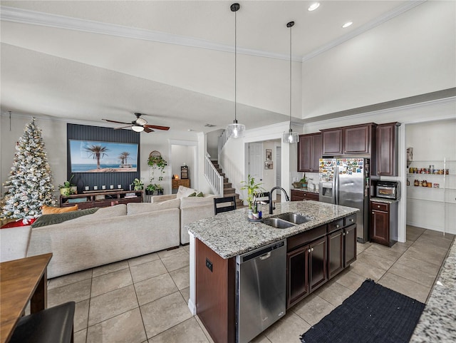 kitchen with ceiling fan, sink, stainless steel appliances, an island with sink, and decorative light fixtures