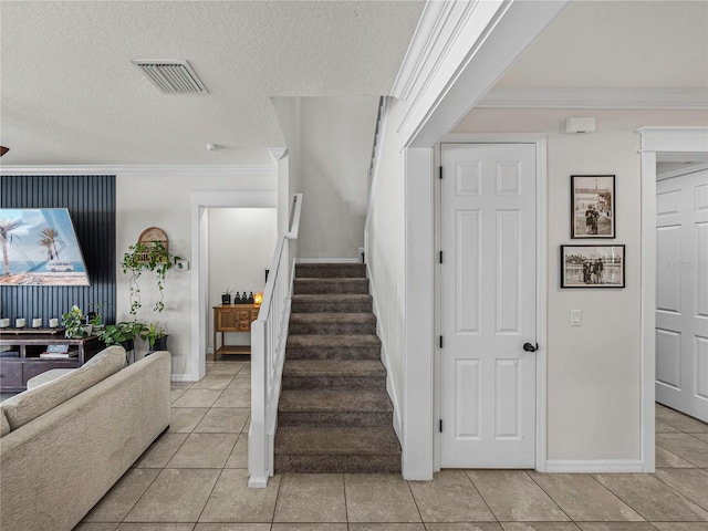 stairs with tile patterned flooring, a textured ceiling, and ornamental molding